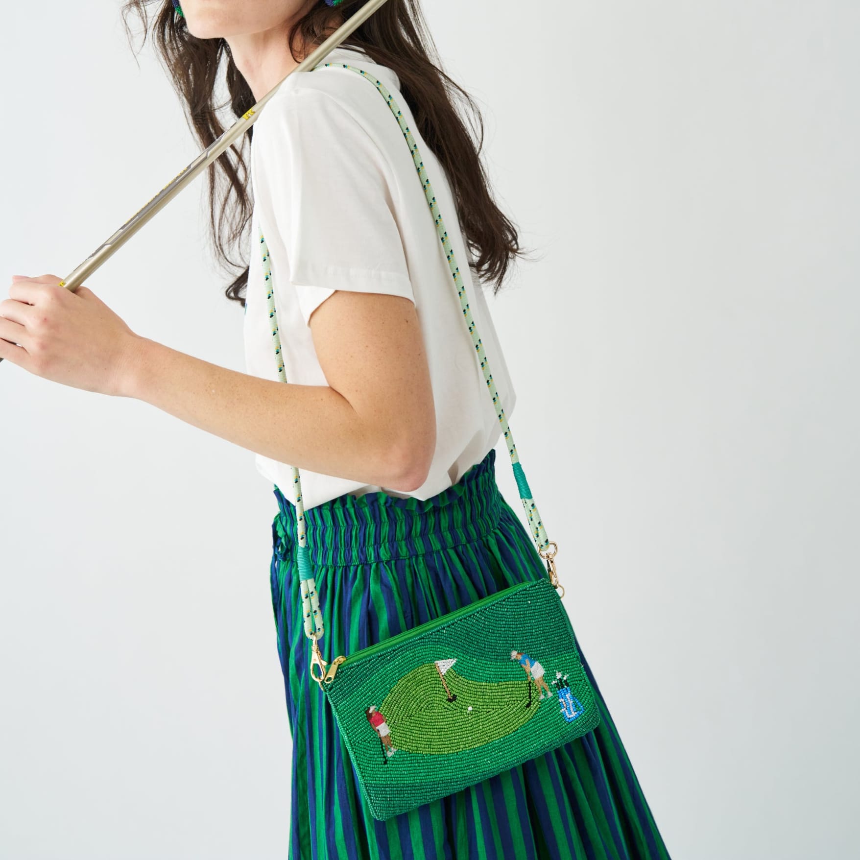 Person wearing a green beaded handbag with a golf design on a white background